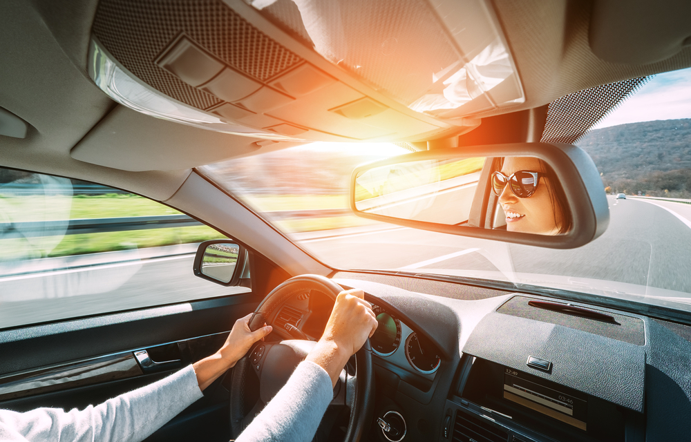 Woman drive a car reflects in back view mirror