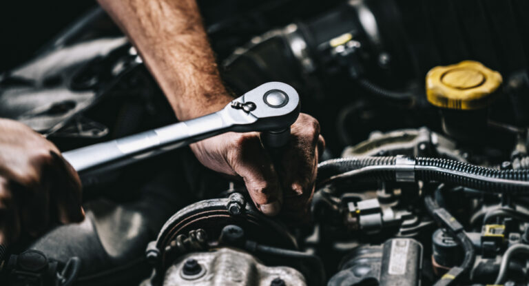 Auto mechanic working on car engine in mechanics garage. Repair service. authentic close-up shot